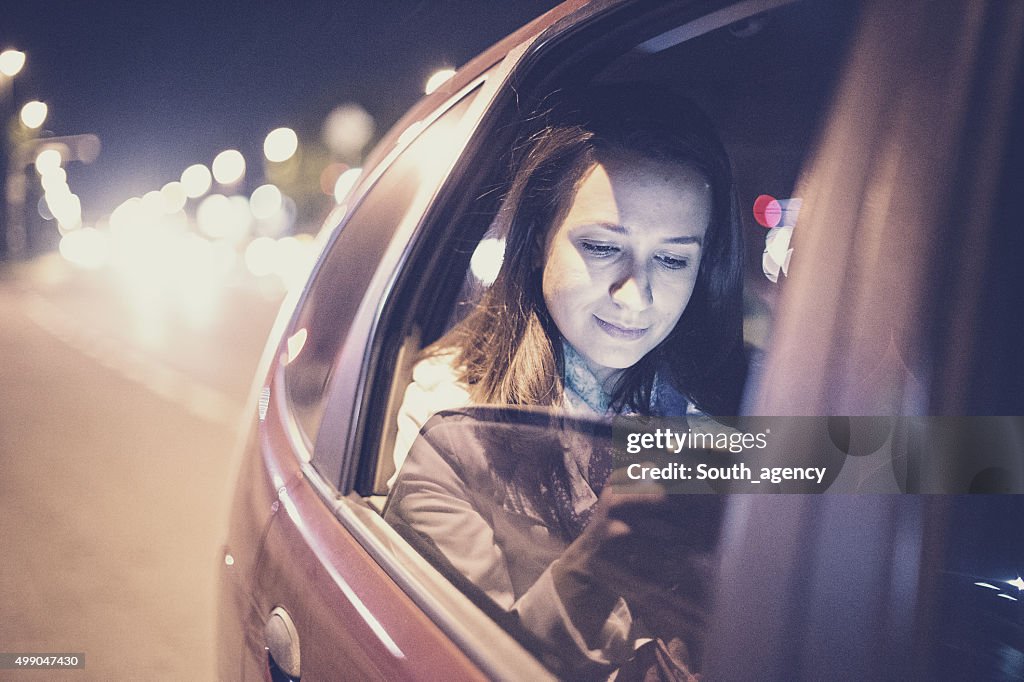 Mulher com smartphone no carro