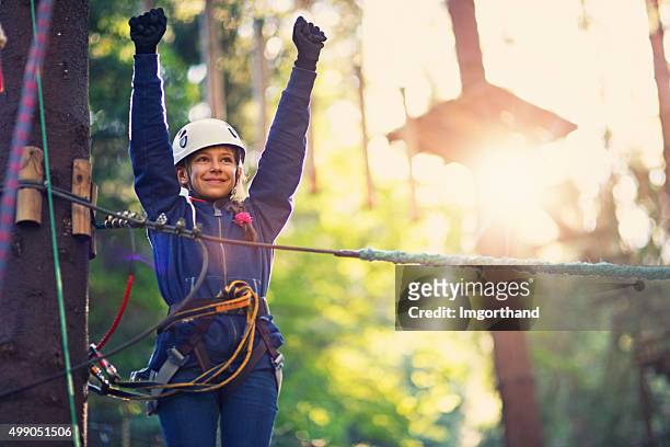 glückliches kleines mädchen, die ropes course adventure park - hochseilgarten stock-fotos und bilder