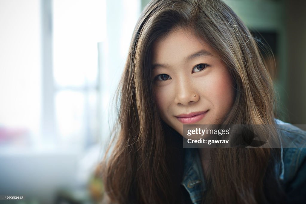 Indoor image of beautiful happy Asian girl looking at camera.