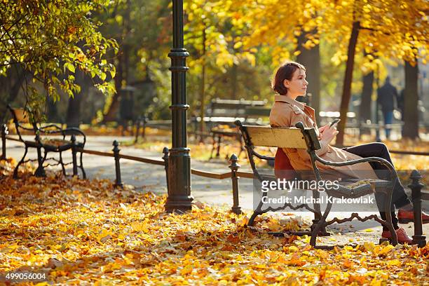 woman sitting on a bench in park in krakow. - krakow park stock pictures, royalty-free photos & images
