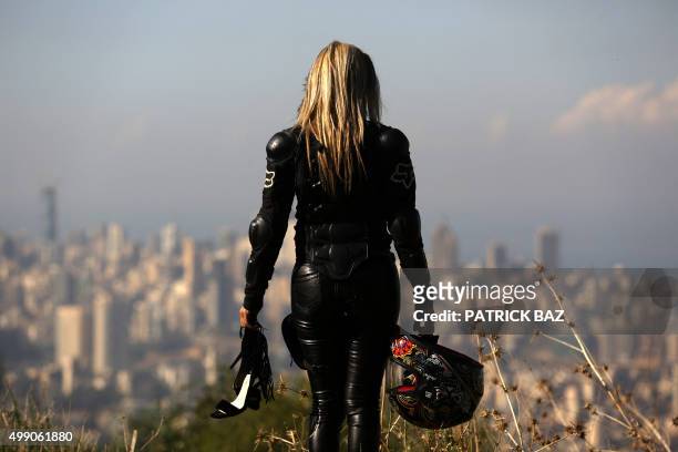Lebanese biker Nissa Hajj holds her high heels and helmet as she poses for a photoshoot on a hill in Mansourieh overlooking the Lebanese capital...