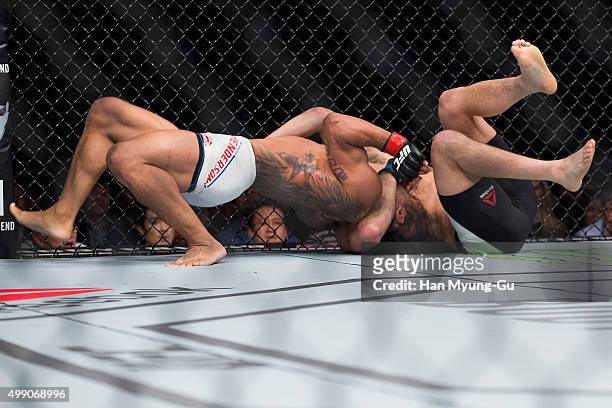 Benson Henderson of the United States of America goes for a submission attempt on Jorge Masvidal of the United States of America in their...
