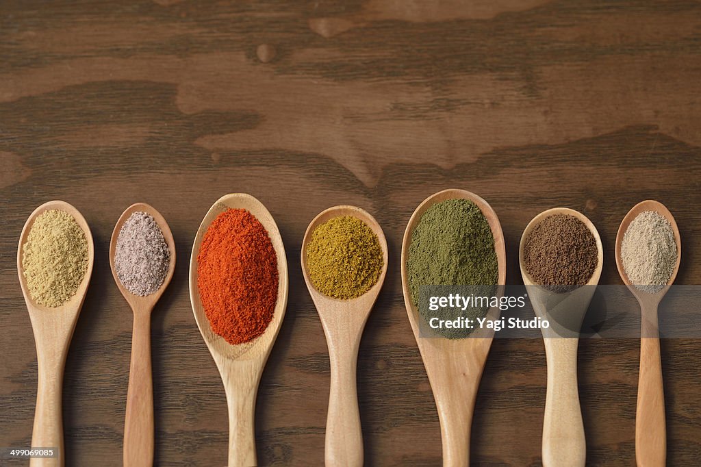 Various colorful spices on wooden spoons