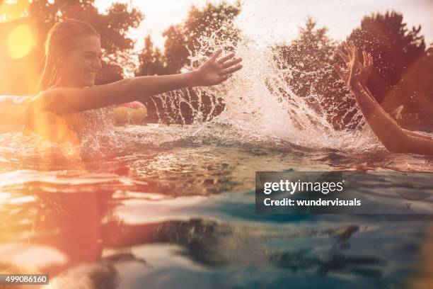 summer swimming pool with girls splashing water playfully - young girls swimming pool stock pictures, royalty-free photos & images