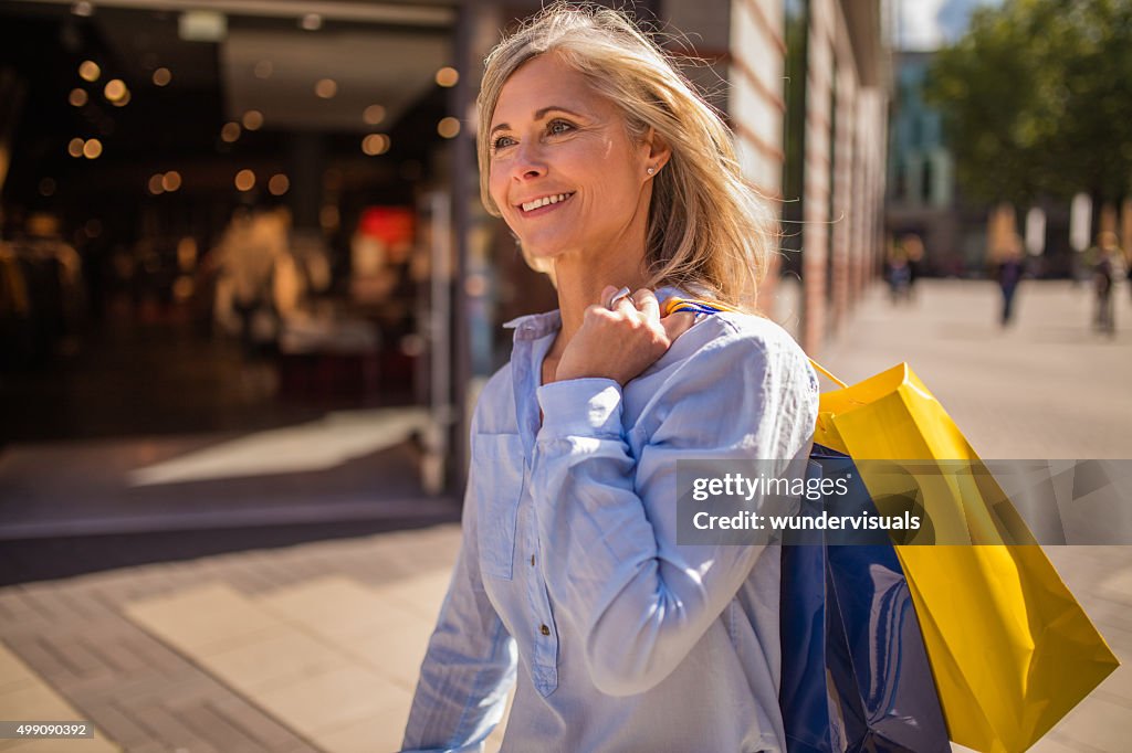Souriant mature Femme marchant avec des sacs dans la ville