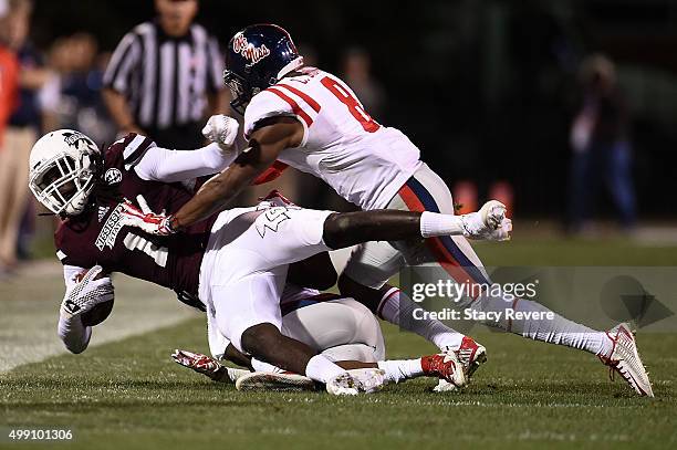 De'Runnya Wilson of the Mississippi State Bulldogs is brought down by Kendarius Webster and Chief Brown of the Mississippi Rebels during a game at...