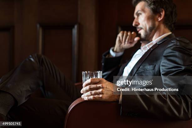 mature man holding whiskey glass - whisky bar stockfoto's en -beelden