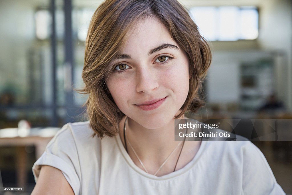 Portrait of young woman in cafe, smiling