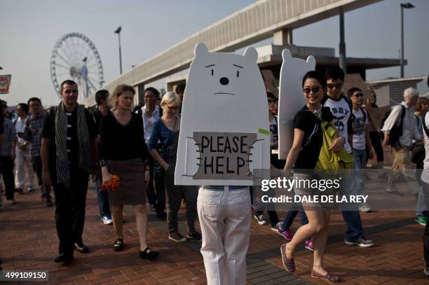 Two women wearing polar bear placards march during a rally calling for action on climate change in Hong Kong on November 29, 2015. Cities around the...