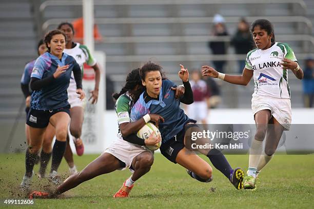 Erica Quichocho of Guam is hauled down by Anusha Attanayaka of Sri Lanka during the World Sevens Asia Olympic Qualification match between Guam and...