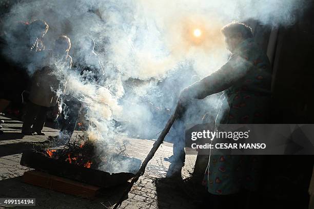 Woman lights a bonfire on November 29 in the northern Spanish village of Arnedillo prior to celebratring the "Procession of smoke". Locals light...