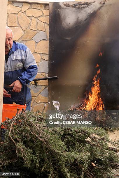 Man carries a bucket as bonfires burn on November 29 in the northern Spanish village of Arnedillo prior to celebratring the "Procession of smoke"....