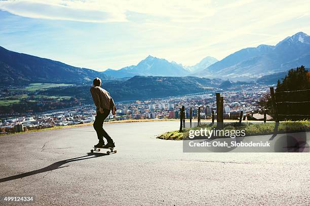 mann reiten auf dem longboard befördert - longboard stock-fotos und bilder