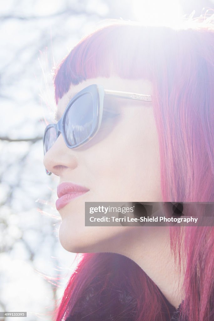 Close up portrait of young woman with pink hair and sunglasses