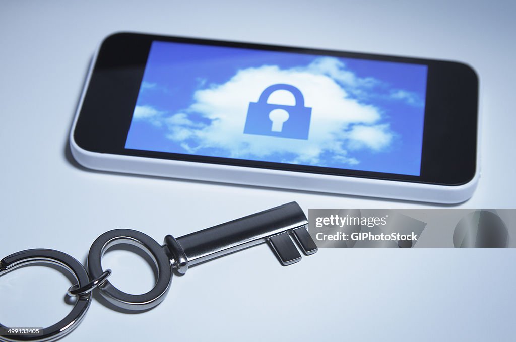 Secure smart phone. A key next to smartphone with a lock over a cloud on its screen.