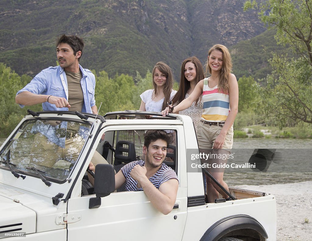 Friends standing on back of off road vehicle