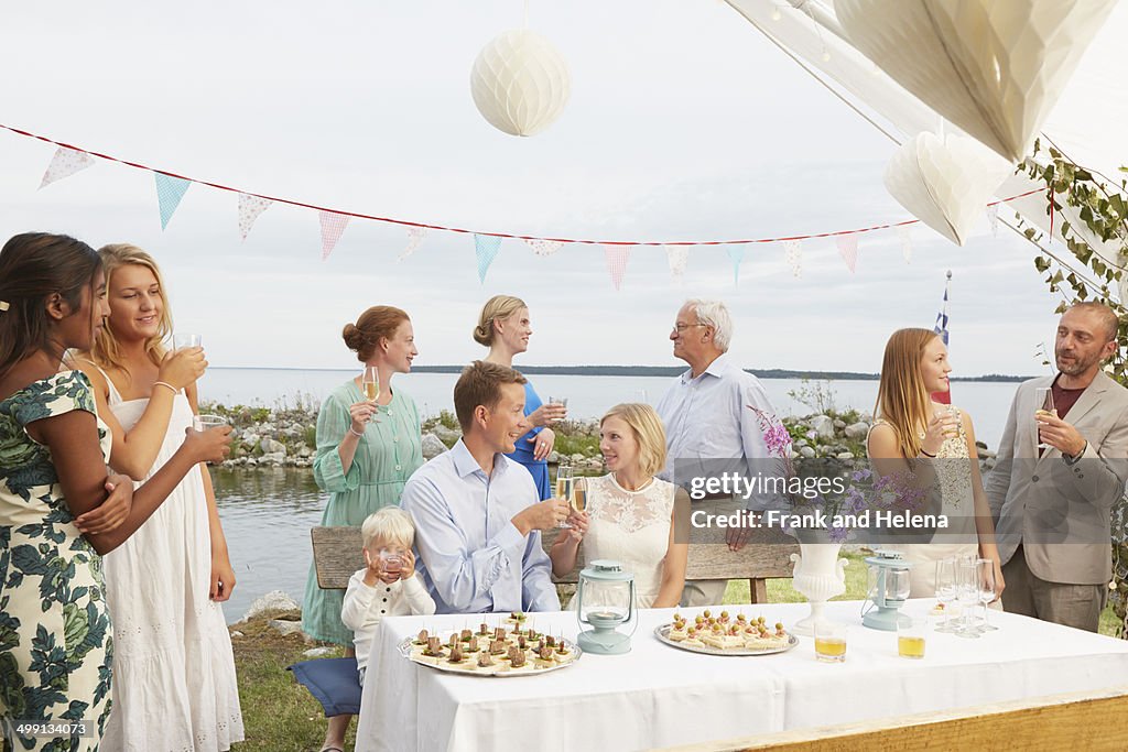 Mid adult couple making a toast with friends at wedding reception