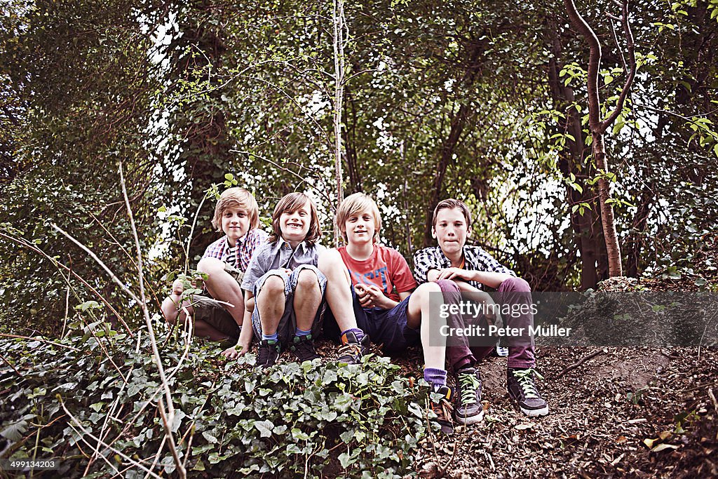 Portrait of four boys sitting in forest