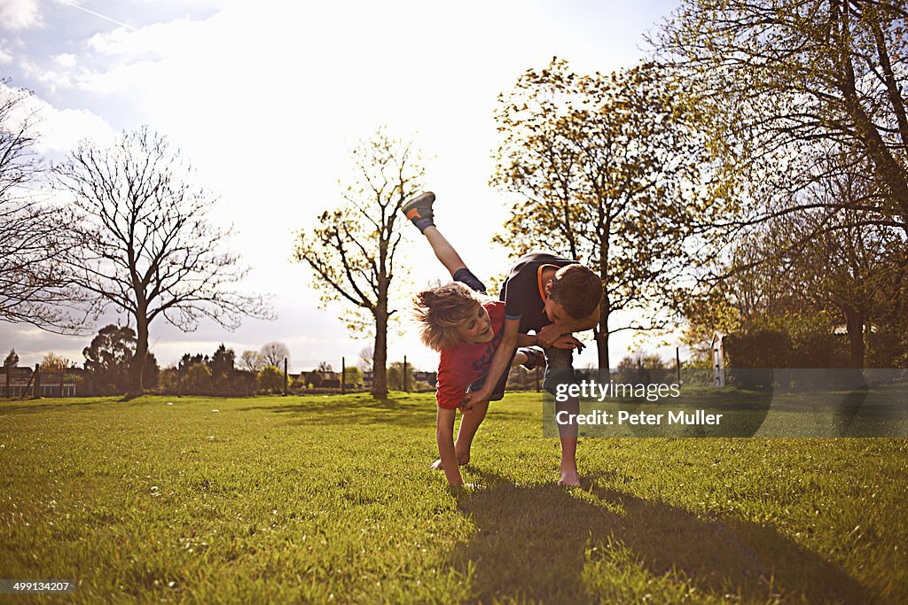 Boys play fighting on playing field