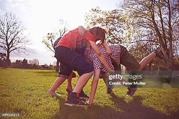 boys play fighting on playing field - rough housing imagens e fotografias de stock