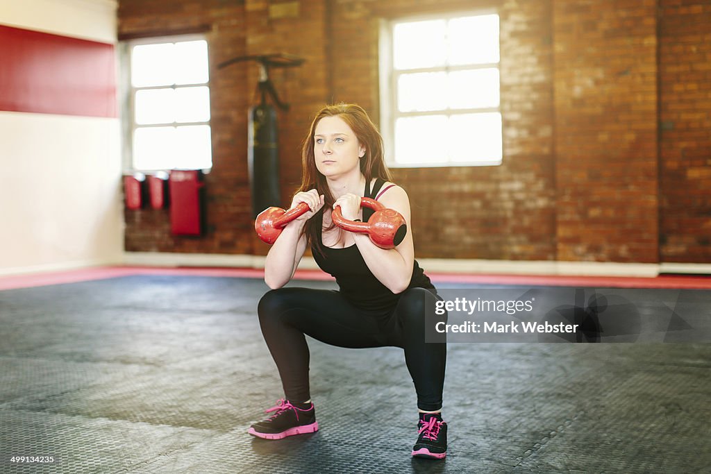 Woman squatting lifting kettlebells