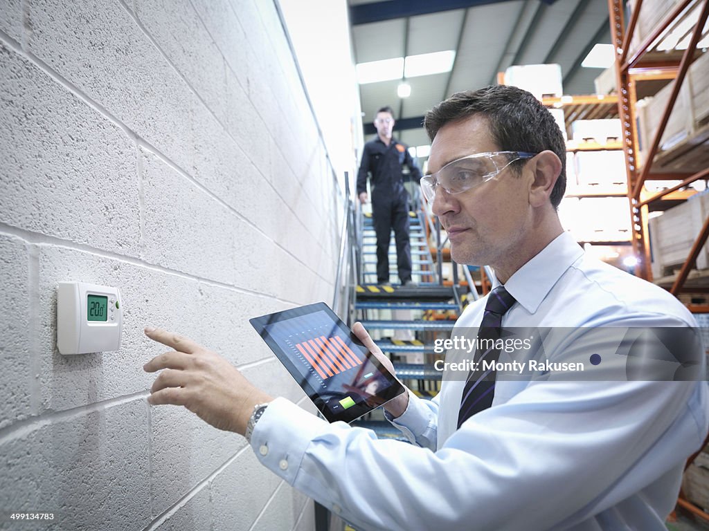 Office worker checking thermostat in factory