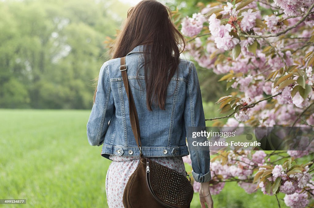 Rear view of young woman strolling in field
