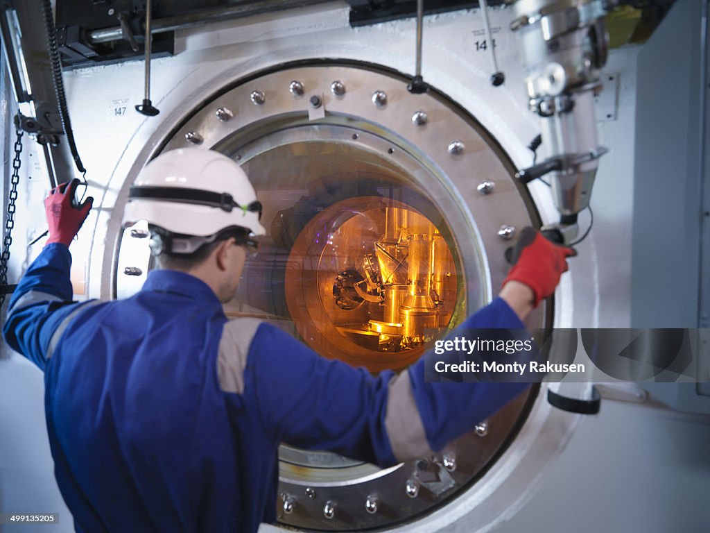 Engineer with fuel rod handling machine in nuclear power station