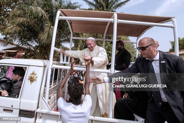 Bodyguard touches the hand of a young woman trying to greet Pope Francis as he leaves after visiting an Internal Displaced people camp at St. Saviour...