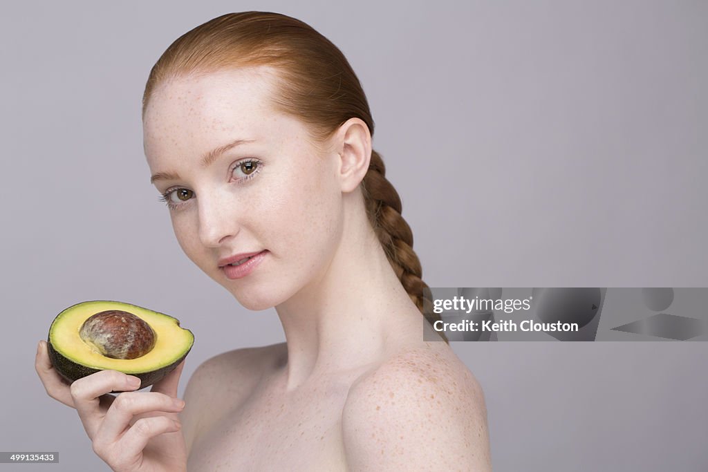 Portrait of young woman, holding avocado