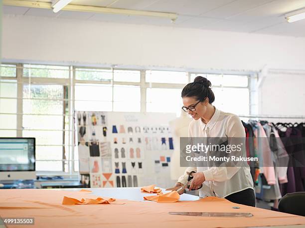 fashion designer cutting cloth in fashion design studio - fashion designer stock pictures, royalty-free photos & images