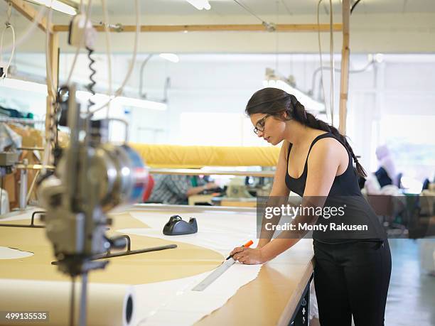 Female garment worker marking cloth in clothing factory