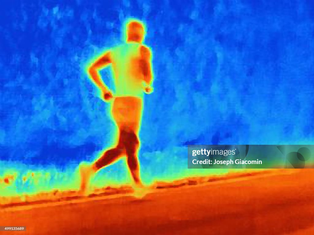 Rear view thermal photograph of young male athlete running. The image shows the heat of the muscles