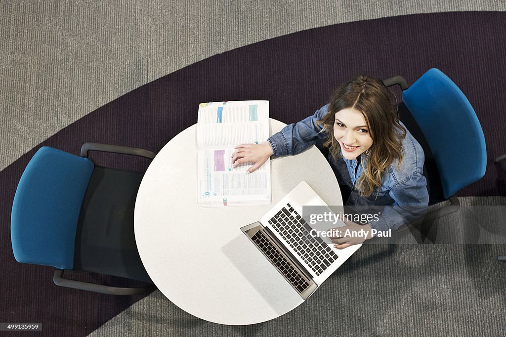Young woman sitting at table using laptop, high angle