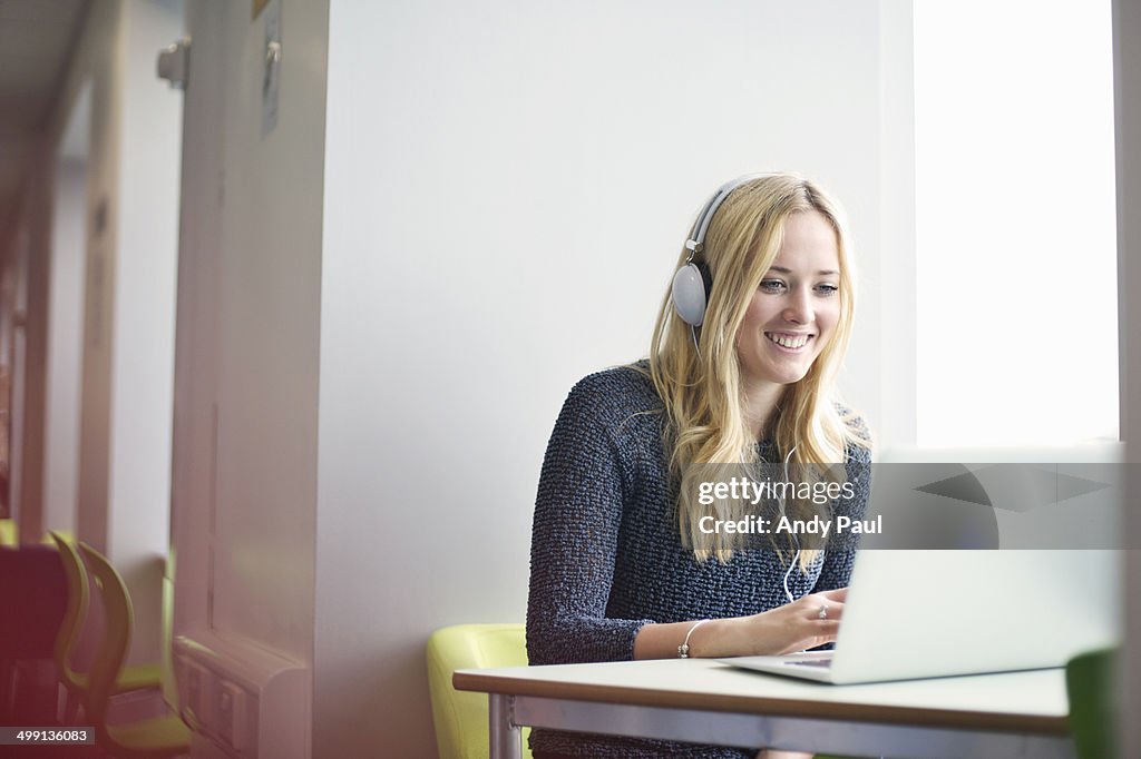 Young woman wearing headphones using laptop