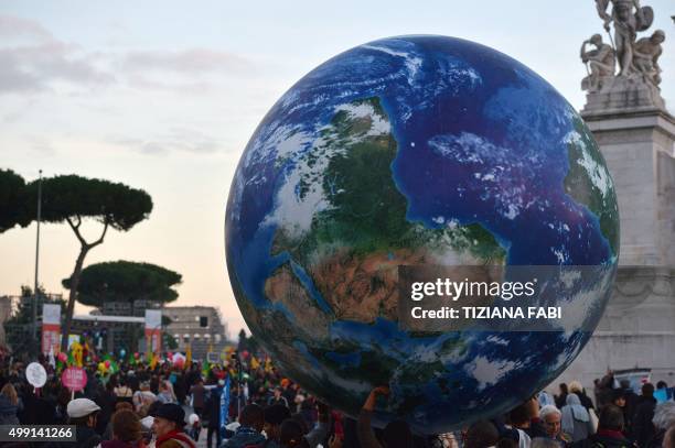 People carry a giant balloon representing Earth during a rally calling for action on climate change on November 29, 2015 in Rome a day before the...