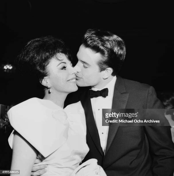 Actor Warren Beatty kisses actress Joan Collins as they attend a party in Los Angeles, California.