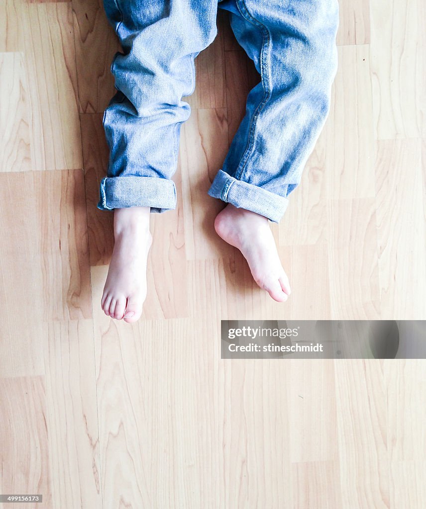 Overhead view of boy's legs lying on floor