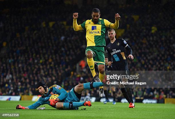 Lewis Grabban of Norwich City jumps over goalkeeper Petr Cech of Arsenal during the Barclays Premier League match between Norwich City and Arsenal at...