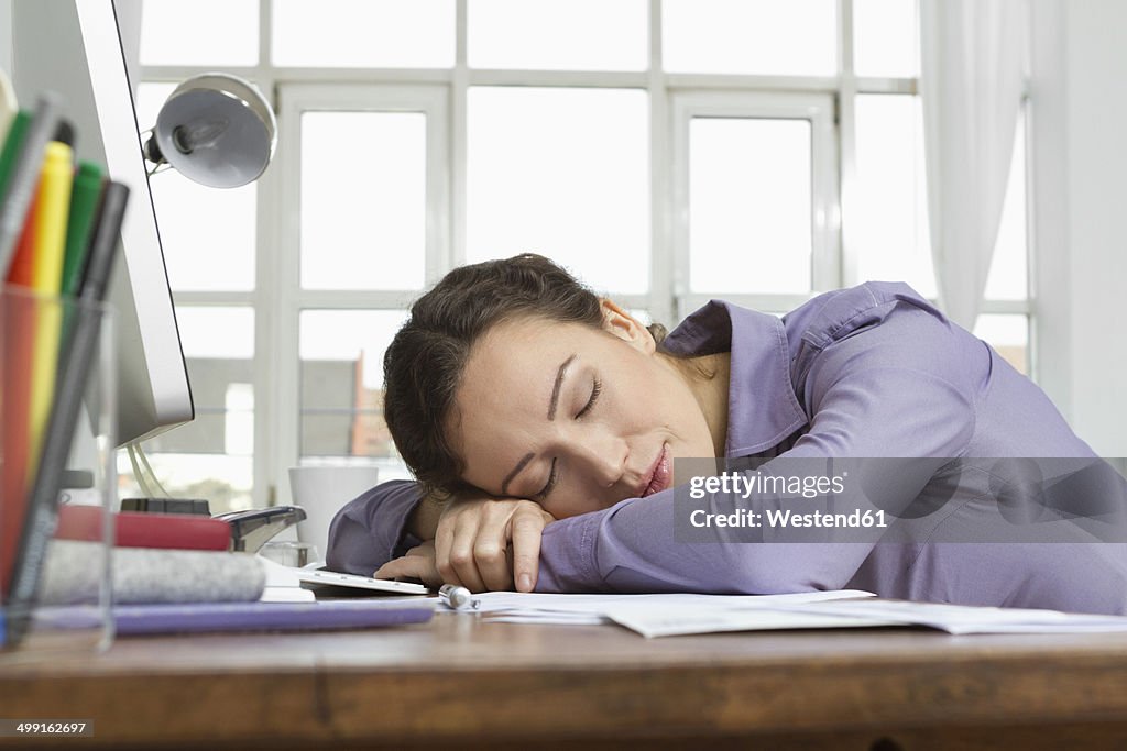 Woman at home sleeping at desk with computer