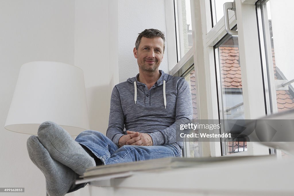 Relaxed man sitting on windowsill