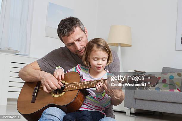 father teaching daughter to play guitar - toddler musical instrument stock pictures, royalty-free photos & images