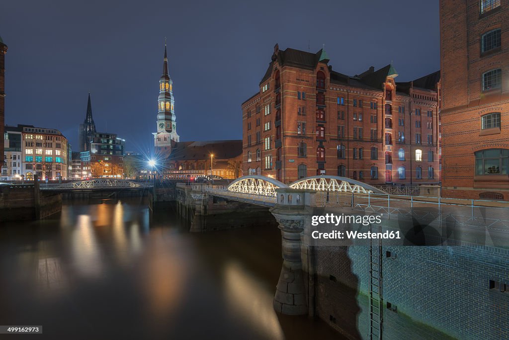 Germany, Hamburg, old warehouse district (Speicherstadt) with St Catherine's church at background by night