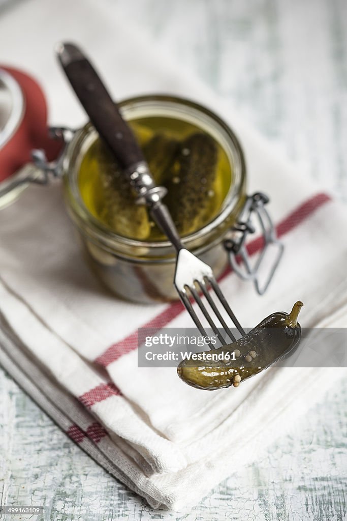 Pickled cornichons in preserving jar and fork