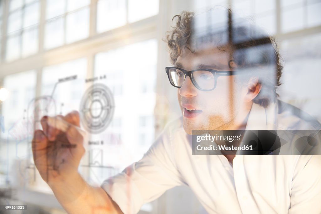 Portrait of young architect marking construction plan in office