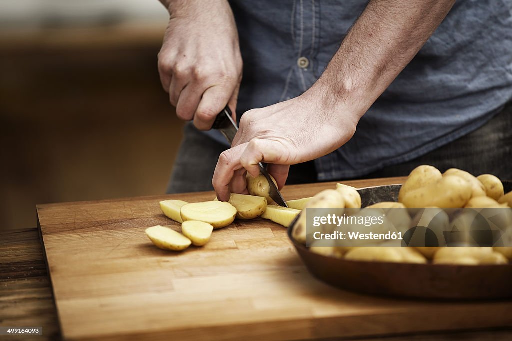 Man cutting potatoes in kitchen