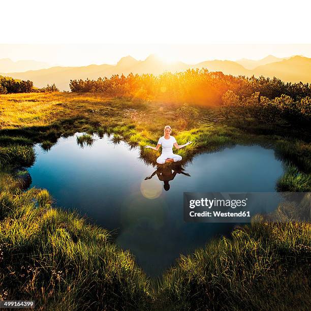 austria, salzburg state, altenmarkt-zauchensee, meditating woman at pond - heart shape in nature stock pictures, royalty-free photos & images