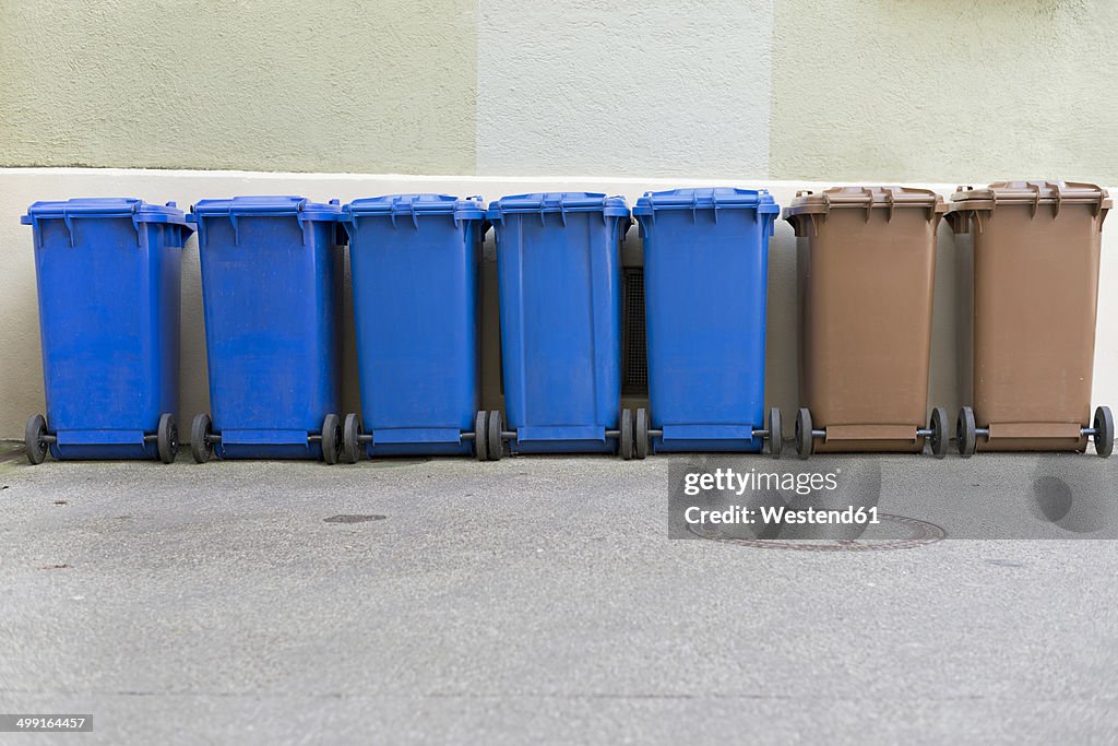 Row of blue and brown garbage cans