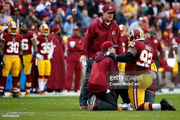 Defensive end Chris Baker of the Washington Redskins is attended to on the field by head coach Jay Gruden of the Washington Redskins after being...