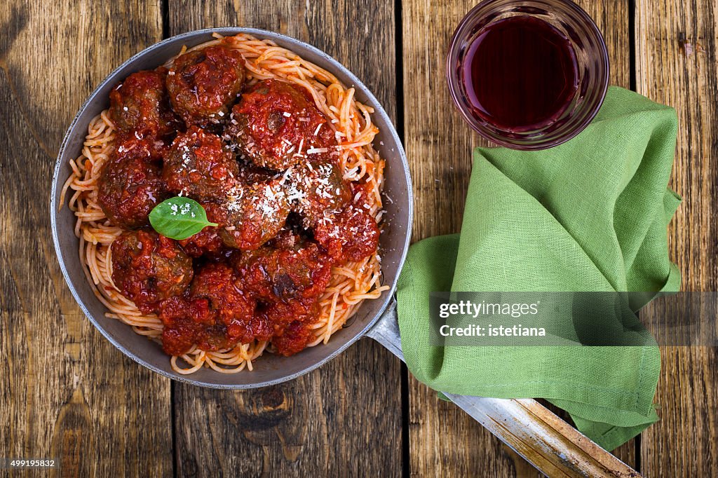 Homemade meatball with Italian pasta in frying pan on  rustic wooden table